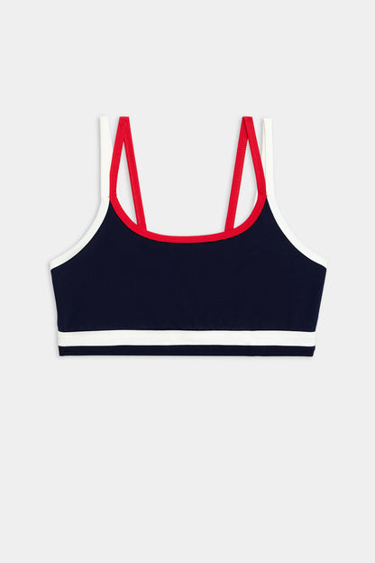 The SPLITS59 Eva Rigor Double Strap Bra in Indigo/White features contrast color accents and double red straps, shown on a plain background—perfect for gym workouts.
