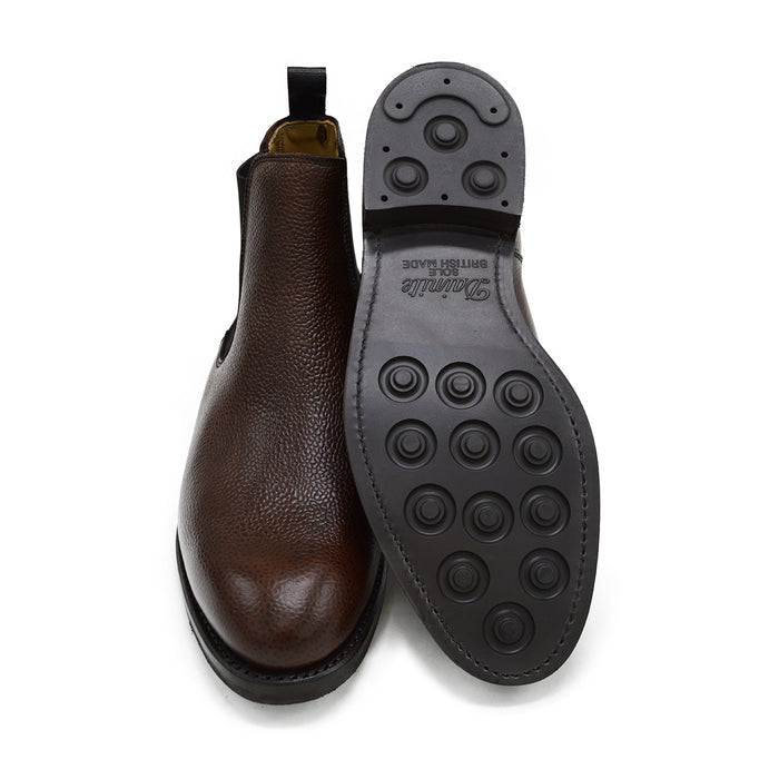 A dark brown grain leather Chelsea boot with a black elastic side panel and a round toe. The boot has a low heel and a goodyear welted dainite rubber sole.
