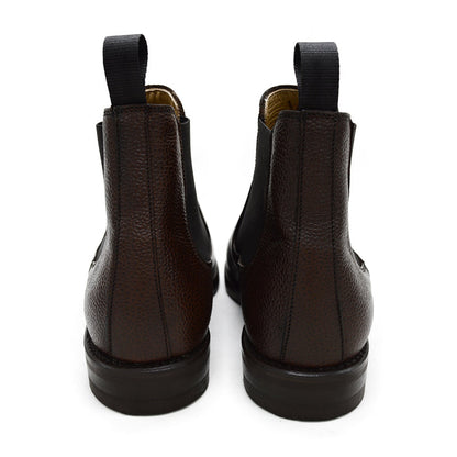A dark brown grain leather Chelsea boot with a black elastic side panel and a round toe. The boot has a low heel and a goodyear welted dainite rubber sole.