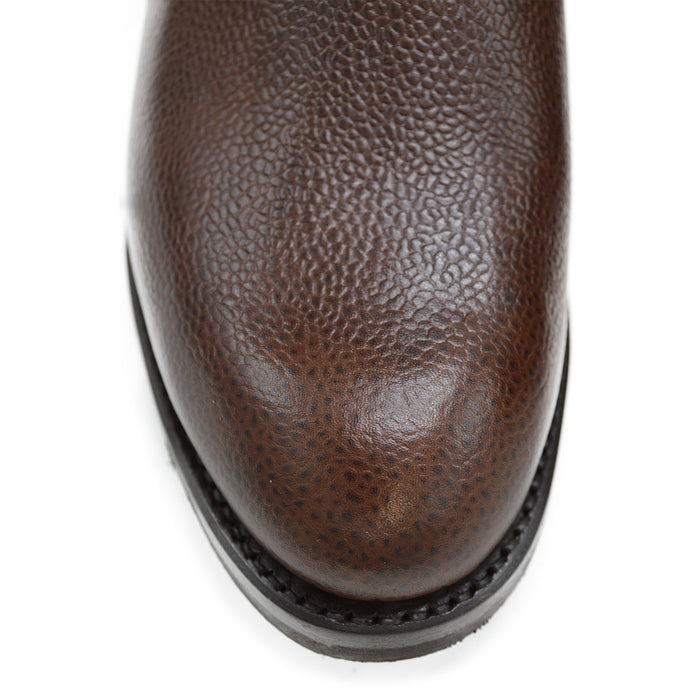 A dark brown grain leather Chelsea boot with a black elastic side panel and a round toe. The boot has a low heel and a goodyear welted dainite rubber sole.