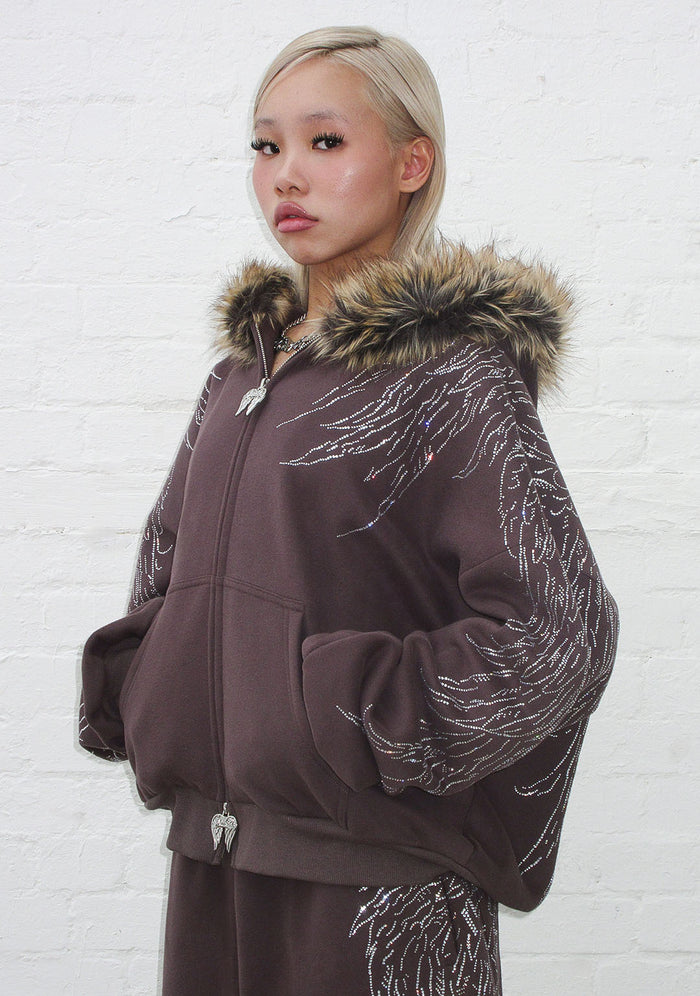 Model wearing the fallen faux fur rhinestone zip hoodie brown, featuring rhinestone wing design and detachable fur trim.