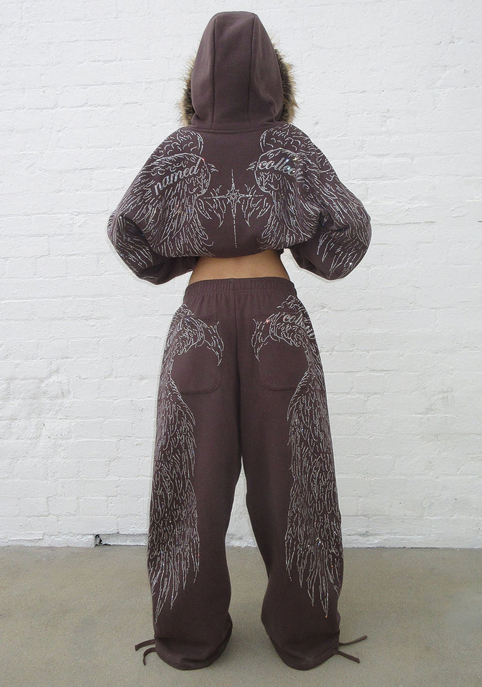 Model wearing brown sweatpants showcasing rhinestone wing design and two back pockets from the back view.