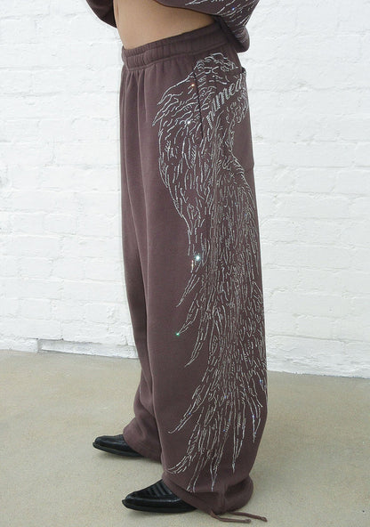 Side view of brown sweatpants with rhinestone wing design and adjustable ankle ties.