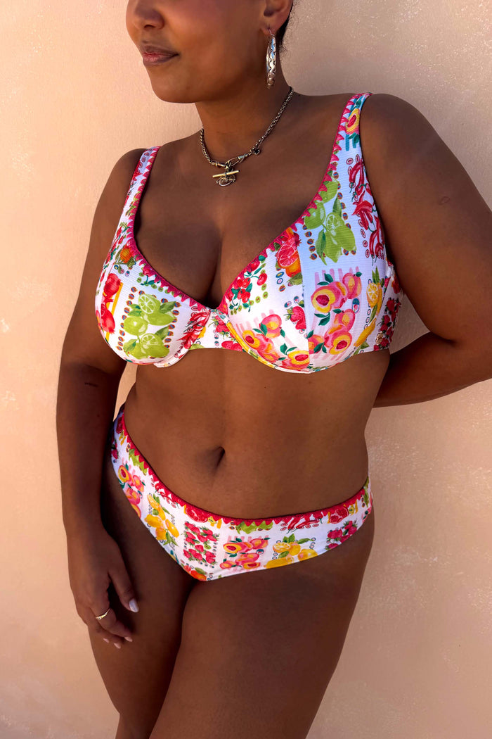 Fruit Stamps Bikini Top featuring a Mediterranean citrus print and pink whipstitch trim, worn on a model.