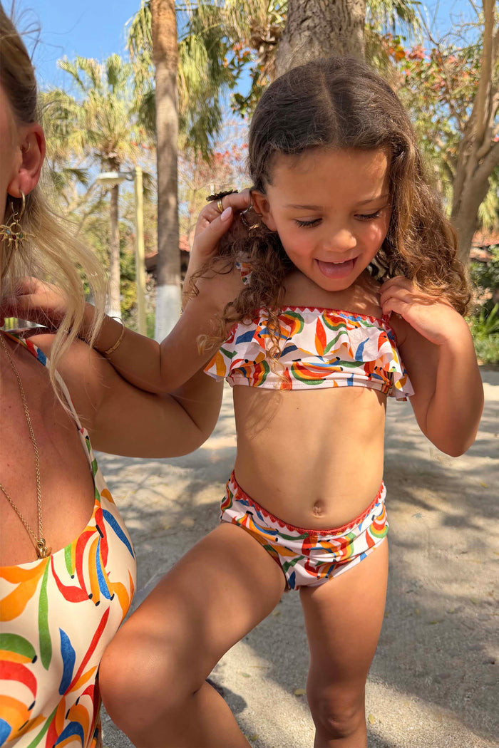 NFD Kids Banana Bikini featuring a multicoloured print, frilled bandeau top and matching bottoms on a sunny vacation.