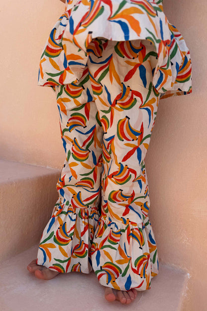 NFD Kids multicoloured banana print cotton trousers with flared ruffled hems and a matching peplum top.