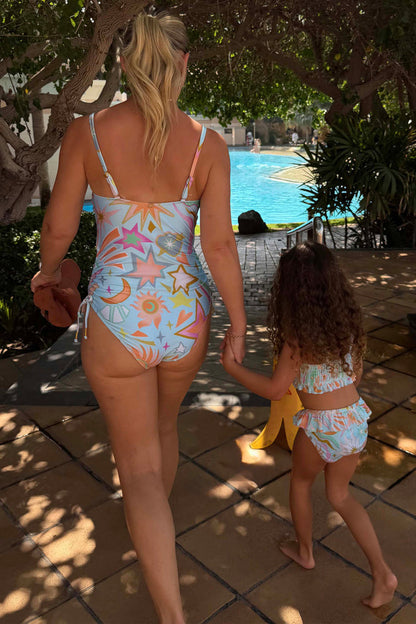 Girl's blue Starburst Crop Bikini Set with frill trims, walking towards a pool on vacation.