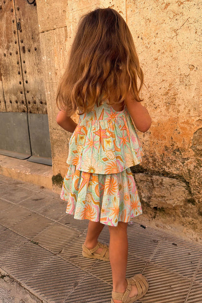 Girl's blue cotton Starburst Skirt Co-ord with a sun and star print, peplum top and tiered skirt, seen from behind.
