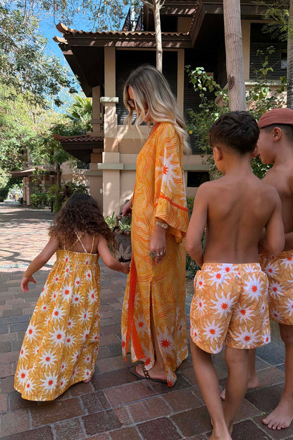 Yellow cotton girl's sun dress with a sun print and shirred top, part of a matching family vacation outfit.