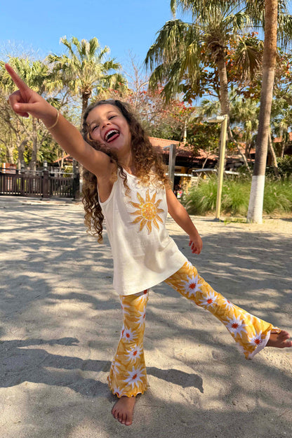 Girl's Yellow Sun Cotton Set with a sequined sun vest and flared soleil sun print trousers at the beach.
