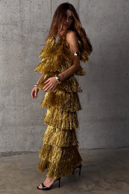 Gold Fringe Dress with tiered gold foil tassels and a midaxi silhouette, worn by a model against a grey wall.