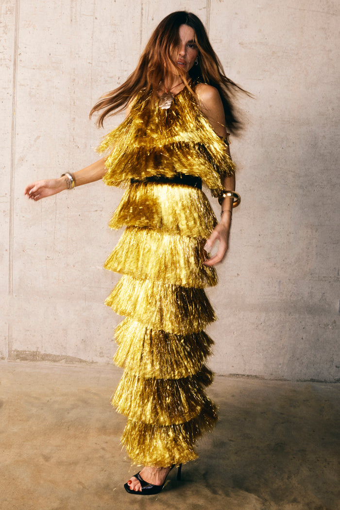 Gold Fringe Dress featuring tiered gold foil tassels and a midaxi length, styled with gold jewelry and black heels.