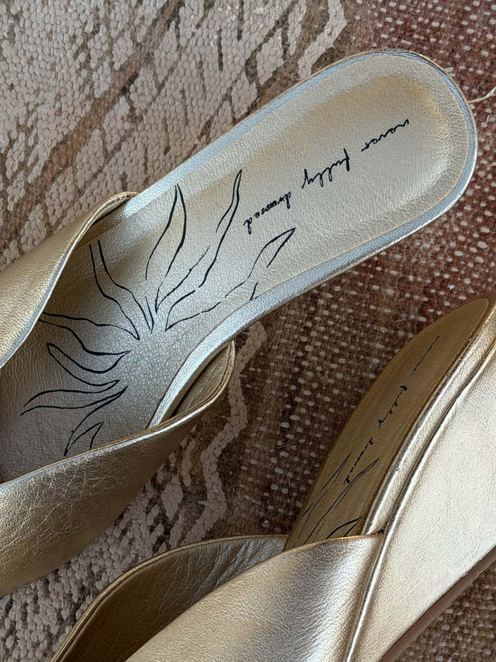 Gold Wedge Mule detail featuring a metallic leather insole with a black sun graphic and brand logo.