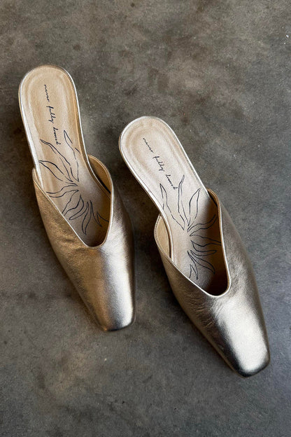 Metallic Gold Wedge Mules with a pointed toe and sculpted heel, featuring a signature graphic on the inner sole.
