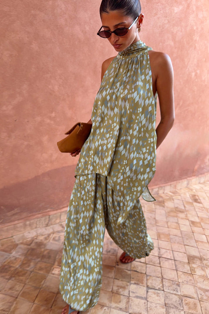 Green Diamond Print Halter Top in olive satin with a draped silhouette, styled with co-ord trousers and sunglasses.