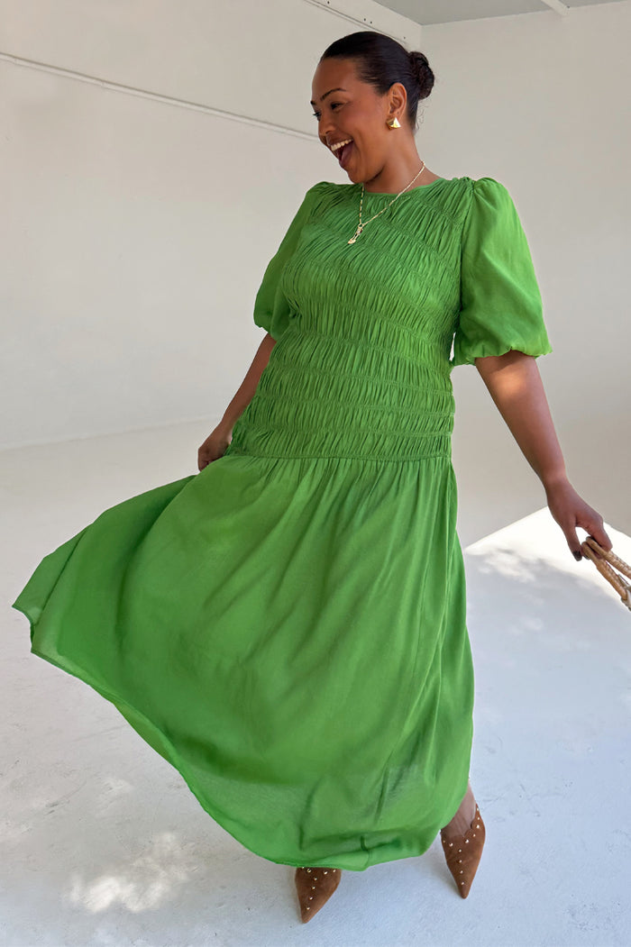 Green Shirred Nara Dress featuring a shirred bodice and short puff sleeves on a smiling model.