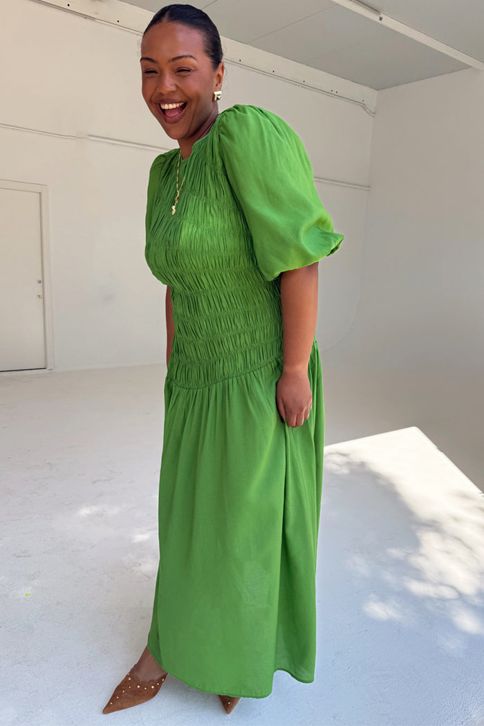 Green Shirred Nara Dress featuring a smocked bodice and puff sleeves, highlighting inclusive sizing on a smiling model.