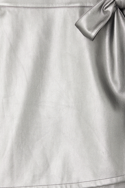 Gunmetal vegan leather detail of the Jaspre mini skirt showing metallic texture and wrap tie fastening.