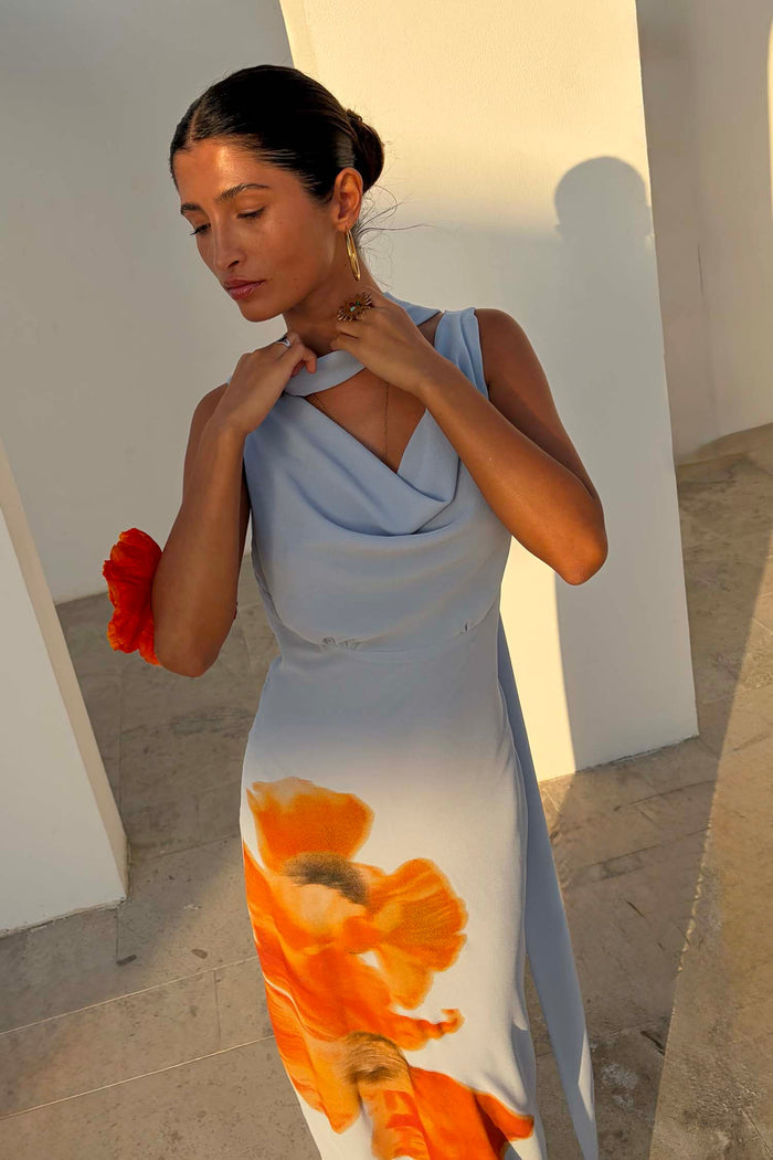Ice Blue Floral Sophie Dress featuring a drape neckline and large orange floral print in a sunlit vacation setting.
