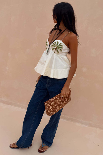 Ivory Palm Nara Top in cotton with green palm motifs, styled with blue jeans and a leopard print clutch bag.