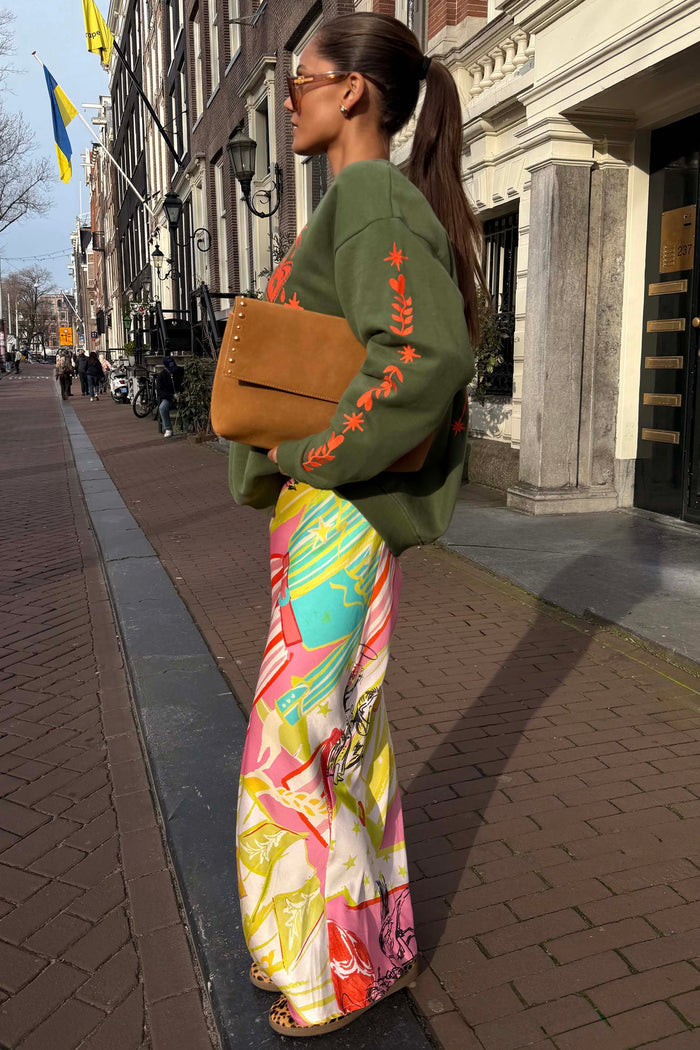 Khaki Sweatshirt with orange embroidery and a colourful patterned skirt for a London street style look.