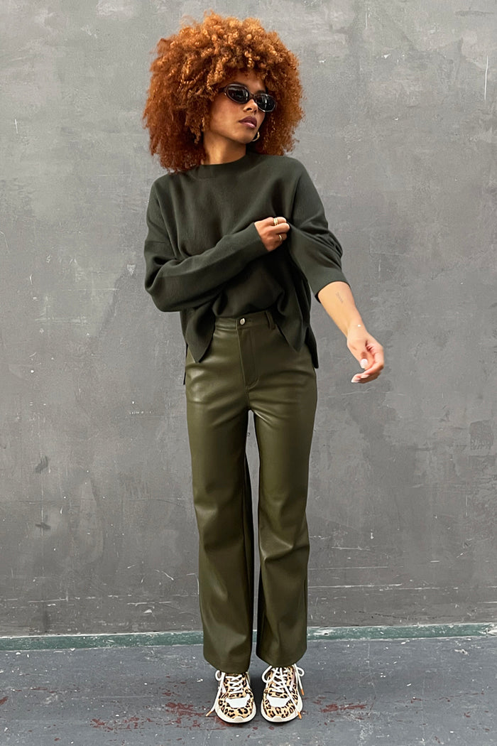 Khaki Vegan Leather Trousers paired with a dark green jumper and leopard print trainers.