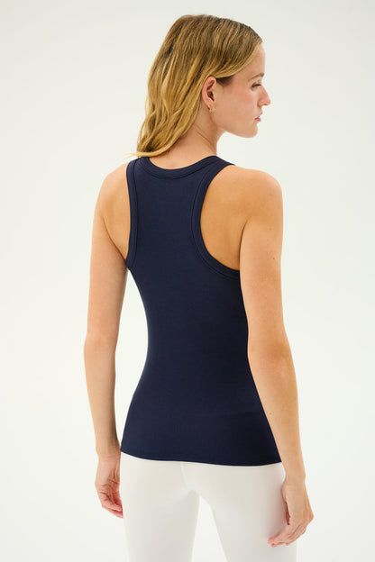 A person with blonde hair is standing and facing away, wearing the SPLITS59 Kiki Rib Tank Full Length in Indigo and white pants.