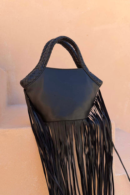 Black Leather Fringe Bag with a plaited handle and long fringe details, resting on a neutral stone background.