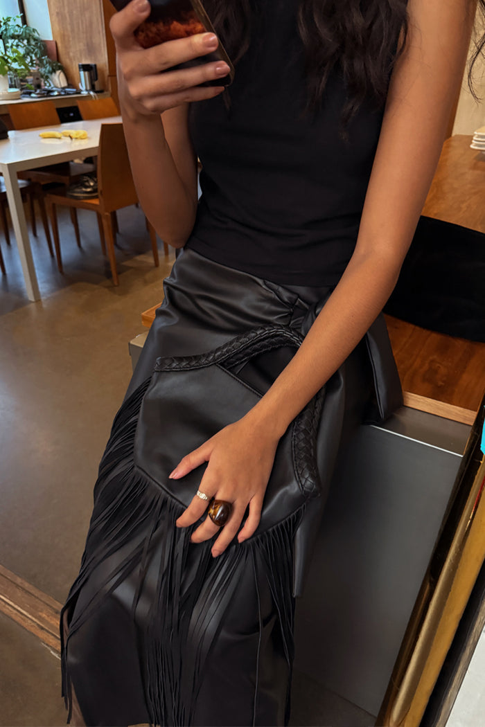 Black Leather Fringe Bag with a plaited handle and long fringes, held by a model in a lifestyle setting.