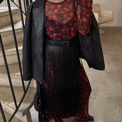 Black Leather Fringe Belt with a wide buckled band and long tassels, layered over a red cherry print dress.