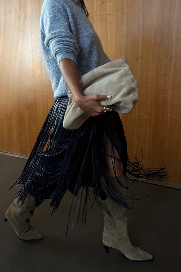 Black leather fringe belt with long tassels, styled with a blue jumper and tan boots for a layered look.