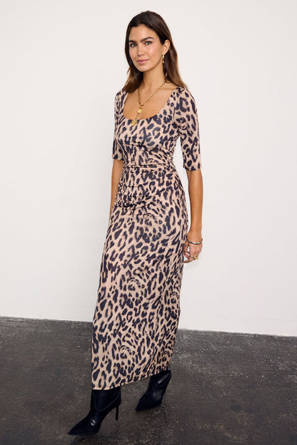 Leopard Iris Dress with ruched waist detail and elbow sleeves, styled with black pointed-toe boots.