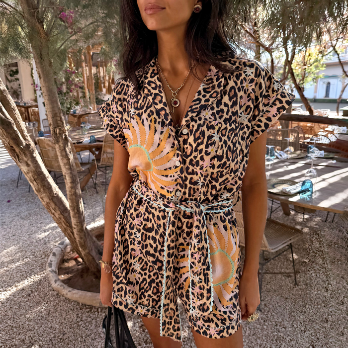 Leopard and soleil print playsuit featuring turquoise trim, a button-through front and adjustable tie waist on a model.
