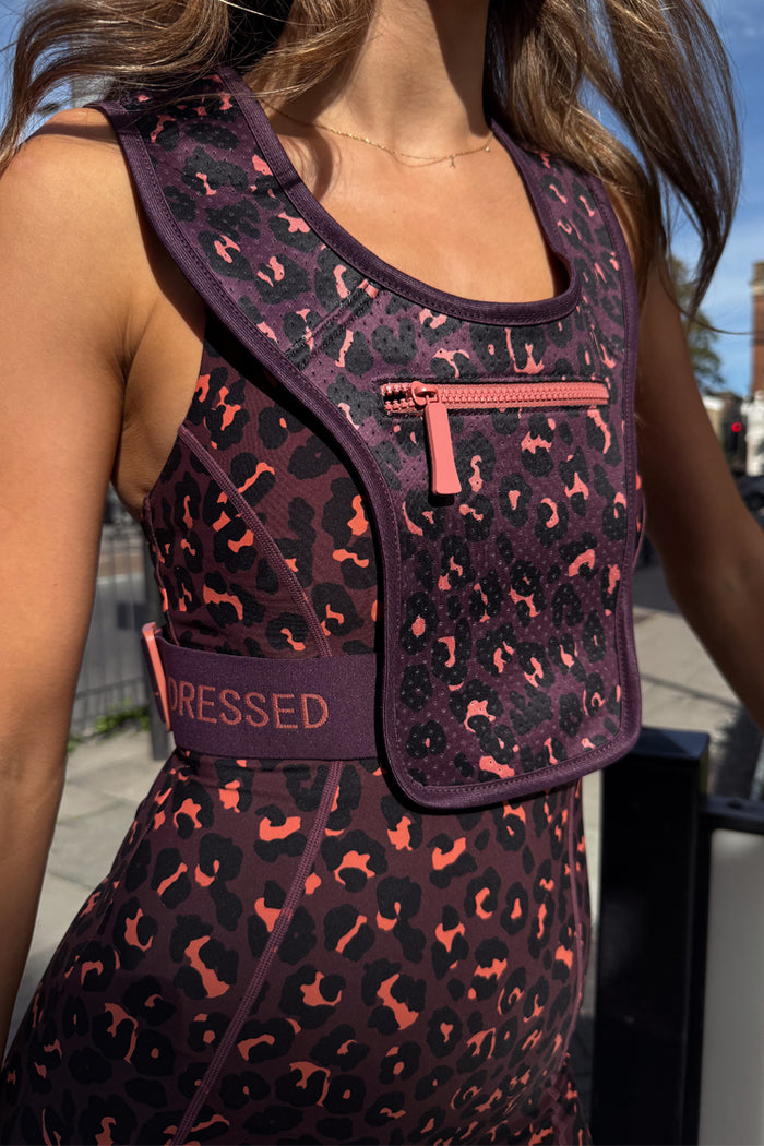 Dark leopard print running bag with a pink front zip and branded strap, worn over matching animal print activewear.