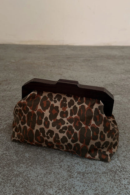 Lucia Leopard Denim Bag with an iconic leopard print and dark wooden handle, shown on a textured grey floor.