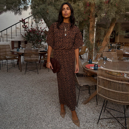 Lucia Leopard Tilly Dress in iconic leopard print plisse, featuring wide sleeves and a midi length in an outdoor setting.
