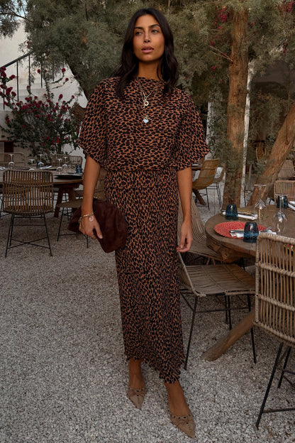 Lucia Leopard Tilly Dress in plisse fabric with an iconic leopard print and elasticated waist at a restaurant.