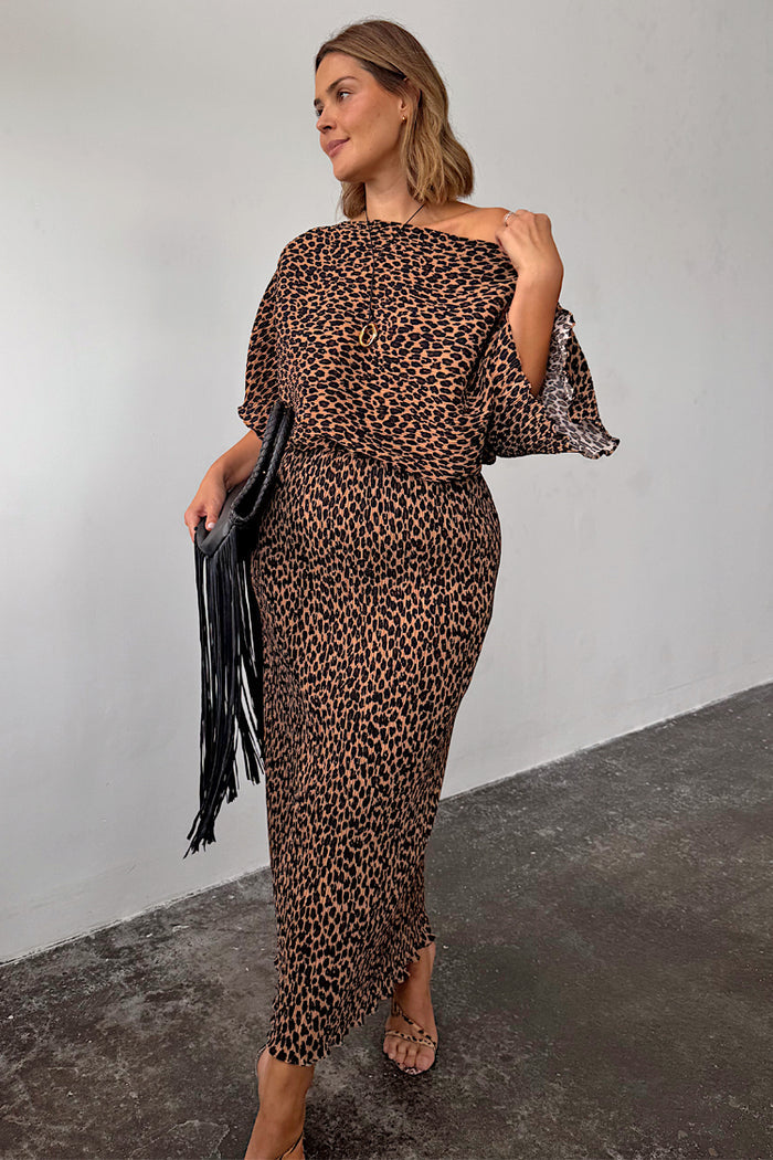 Lucia Leopard Tilly dress in plisse fabric, styled off-the-shoulder and paired with a black fringe clutch.