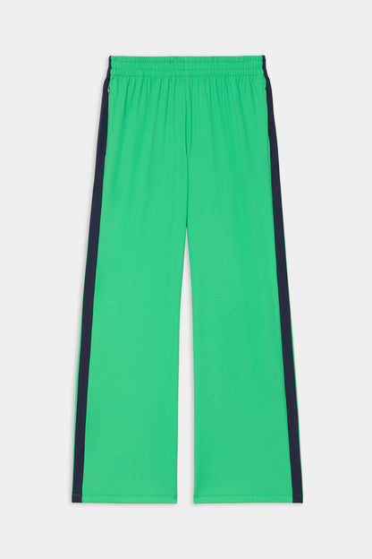 The SPLITS59 Maxie Rigor Trackpant in Grass/Indigo features a bright green wide-leg design, elastic waistband, and dark indigo side stripes, shown laid flat on a white background.
