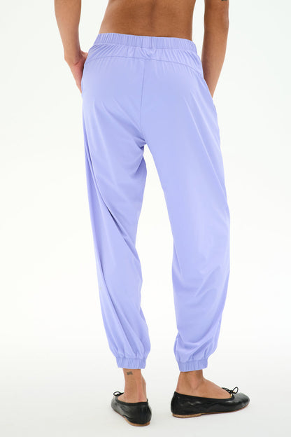 Person wearing SPLITS59 Megan Woven Nylon Jogger in Purple Haze and black ballet flats, shown from the back against a plain white background.