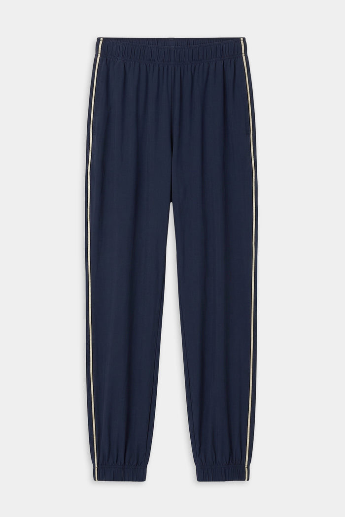 The SPLITS59 Megan Woven Nylon Jogger w/ Piping in Indigo/Creme features an elastic waistband and cuffs, white side piping, and is crafted from stretchy fabric for comfort and flexibility.