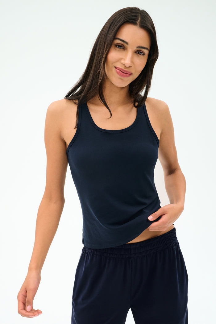 Model wears the SPLITS59 Mel Airweight Lite Tank in Indigo, paired with matching pants, standing against a plain light background.