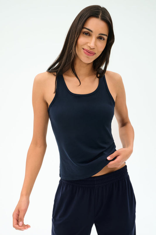 Model wears the SPLITS59 Mel Airweight Lite Tank in Indigo, paired with matching pants, standing against a plain light background.