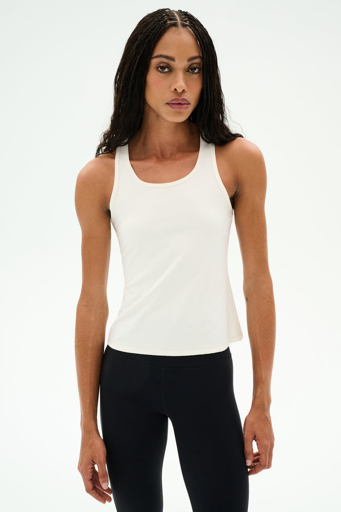 Woman wearing the SPLITS59 Mel Airweight Lite Tank in white, standing against a plain white background—ideal for Pilates or hot yoga.