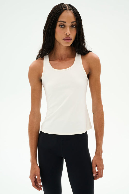 Woman wearing the SPLITS59 Mel Airweight Lite Tank in white, standing against a plain white background—ideal for Pilates or hot yoga.