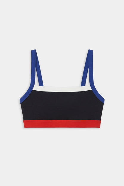 The SPLITS59 Monah Rigor Bra - Black/Cobalt features a color-blocked design with blue straps, a white upper band, black body, and red lower band—ideal for workouts. Shown on a white background.