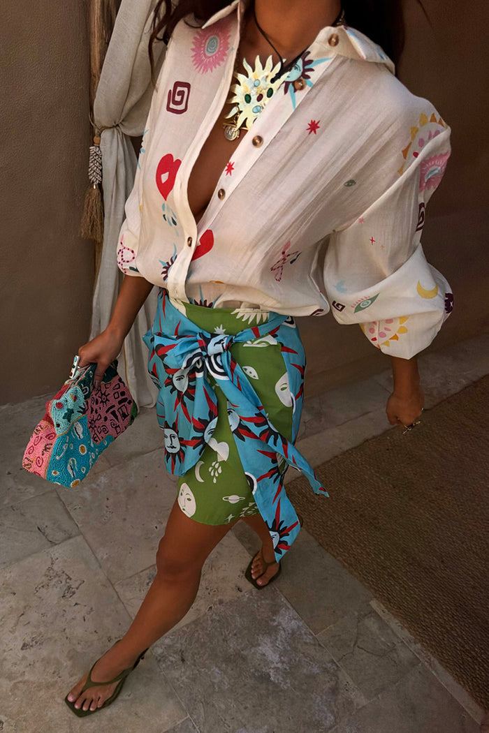 Morocco Mini Wrap Skirt with green and blue sun face prints, featuring a wrap tie fastening for a multi-wear look.