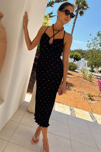 Multi Spot Megan Dress in black plisse with multicoloured flecks and cross-front straps, styled for a summer vacation.