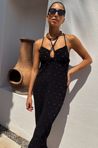 Multi Spot Megan Dress in black plisse with colourful flecks and a crossover strappy neckline on a model.