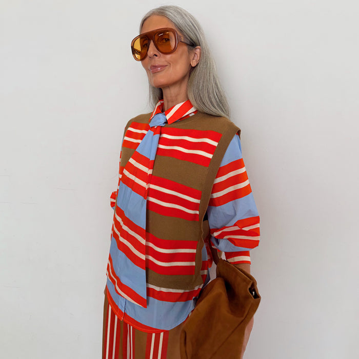Multi Stripe Tank Top in tan and red knit, layered over a blue striped shirt on a model with silver hair.